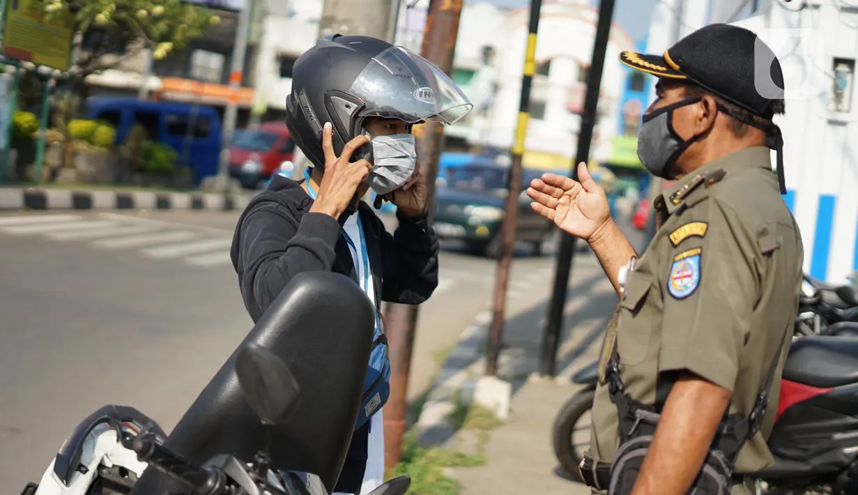 Petugas melakukan sosialisasi penggunaan masker kepada pengendara sepeda motor di kawasan Depok, Jawa Barat, Senin (20/7/2020). Warga yang tidak mengenakan masker nantinya akan dikenai denda Rp 50 ribu atau sanksi sosial sesuai Perwali Nomor 45 tahun 2020. (Liputan6.com/Immanuel Antonius)