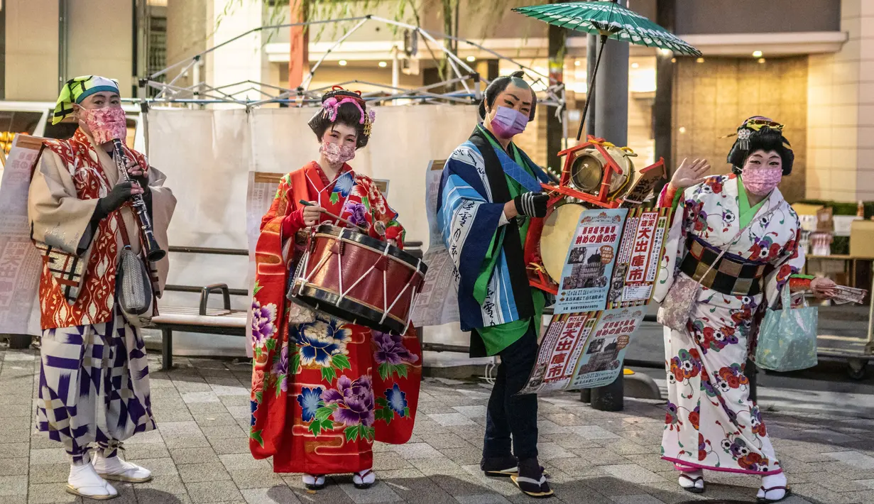 Orang-orang yang mengenakan kimono berbaris di jalan saat mereka mengiklankan pekan raya akhir tahun di Distrik Nihonbashi, Tokyo, Jepang, 26 Desember 2022. Tak hanya menyuguhkan pemandangan indah dan makanan yang lezat, Jepang juga menjadi negara yang tepat untuk merayakan tahun baru. (Yuichi YAMAZAKI/AFP)