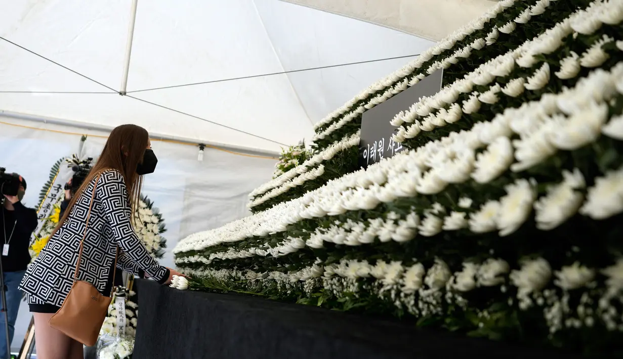 Seorang pelayat meletakkan bunga untuk memberikan penghormatan bagi para korban tragedi Halloween Itaewon di altar peringatan bersama yang dipasang dekat tempat kejadian di Seoul, Korea Selatan, Senin (31/10/2022). Tragedi Halloween Itaewon menewaskan lebih dari 150 orang dan menjadi bencana terburuk Korea Selatan dalam beberapa tahun. (AP Photo/Lee Jin-man)
