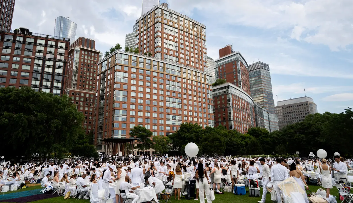Ribuan orang berpakaian serba putih berkumpul dalam Diner en blanc di Rockefeller Park, New York, Rabu (17/7/2019). New York City Diner en Blanc adalah sebuah pesta makan malam rahasia dengan pakaian bernuansa putih yang diadopsi dari budaya Prancis. (Eric Vitale/Diner en Blanc International via AP)