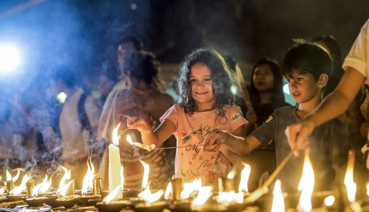 Anak-anak menyalakan lilin dalam kegiatan Earth Hour Internasional di Myanmar (25/3). Tahun ini gerakan Earth Hour melibatkan pemadaman listrik selama satu jam di 7.000 kota di 172 negara. (AFP/Ye Aung Thu)