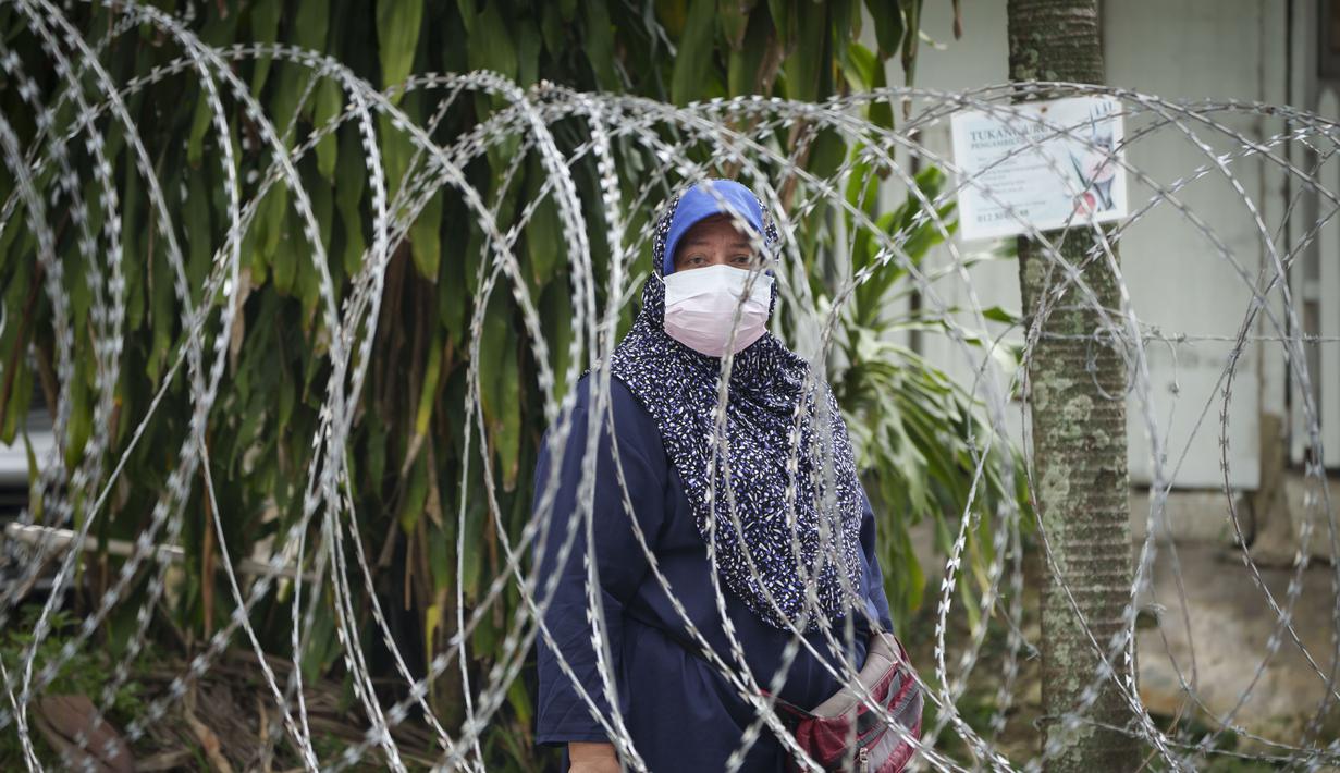 Warga berdiri di belakang kawat berduri di Segambut Dalam yang ditempatkan di bawah EMCO di Kuala Lumpur, Malaysia (27/6/2021). Pemimpin Malaysia mengatakan penguncian total satu bulan yang akan berakhir Senin akan diperpanjang karena infeksi virus corona tetap tinggi. (AP Photo/Vincent Thian)