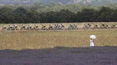 Seorang wanita dengan gaun dan payung putih menonton balapan Tour de France etape ke-19 dengan jarak tempuh 222,5 km dari Embrun menuju Salon-de-Provence, Prancis, (21/7/2017). (AP/Christophe Ena)
