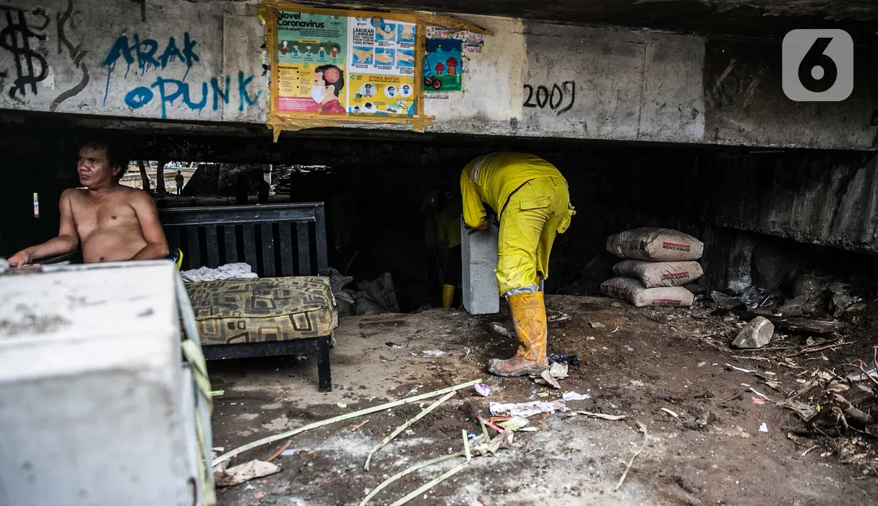 Petugas Sudin Bina Marga Provinsi DKI Jakarta merapikan kolong jembatan usai dihuni pemulung di Kelurahan Pegangsaan, Kecamatan Menteng, Kamis (7/1/2021). Penataan kolong jembatan bertujuan agar tempat itu tidak dijadikan tempat tinggal bagi tunawisma atau pemulung. (Liputan6.com/Faizal  Fanani)