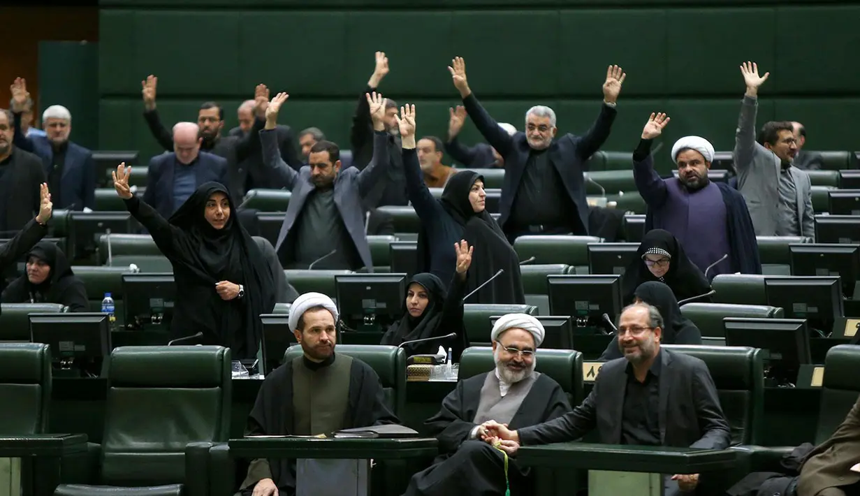 Anggota parlemen Iran mengangkat tangan saat voting RUU yang menetapkan pasukan militer Amerika Serikat sebagai teroris, Teheran, Selasa (7/1/2020). Parlemen Iran menetapkan pasukan militer Amerika Serikat teroris sebagai tanggapan atas kematian Jenderal Qasem Soleimani. (ICANA NEWS AGENCY/AFP)