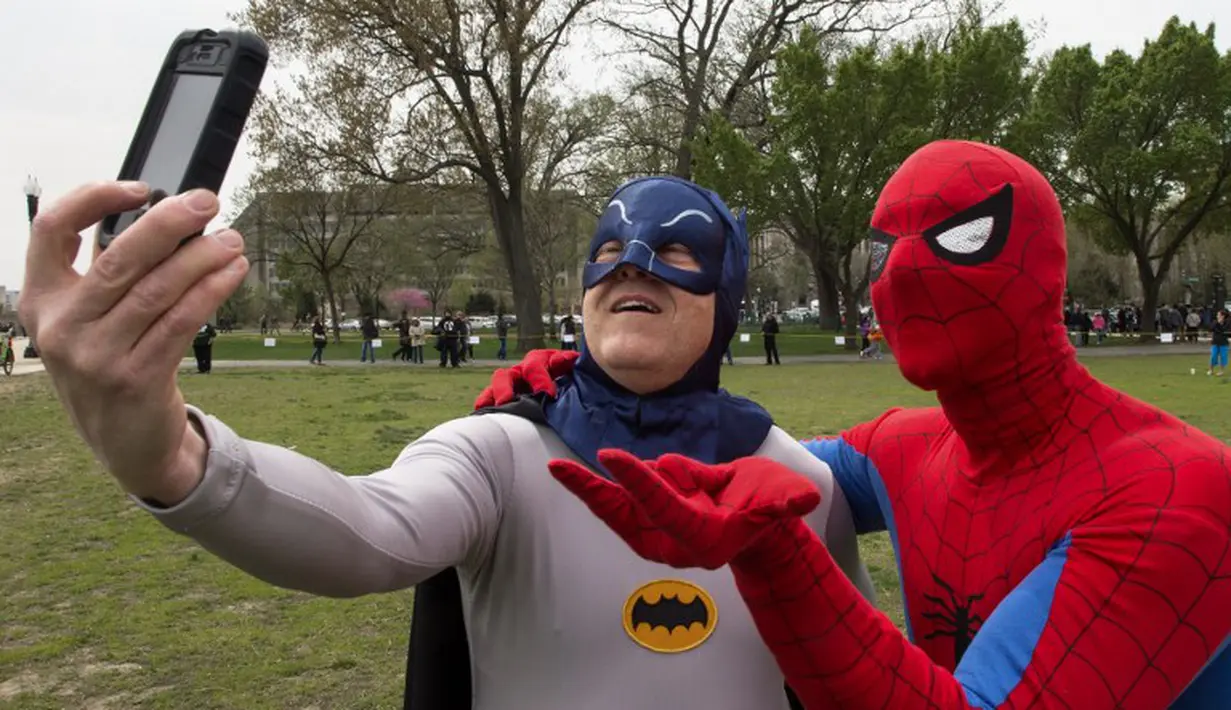 Dua pria bertopeng Spiderman dan Batman berfoto selfie saat memecahkan rekor dunia untuk karakter buku komik terbanyak dunia, Washington DC, (18/4/2014) (AFP Photo/Paul J. Ricards).