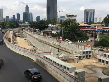 Kendaraan melintas di samping pembangunan proyek underpass Mampang-Kuningan, Jakarta, Senin (29/1). Underpass dengan panjang 860 meter ini kemungkinan besar baru bisa rampung pada April 2018 mendatang. (Liputan6.com/Immanuel Antonius)