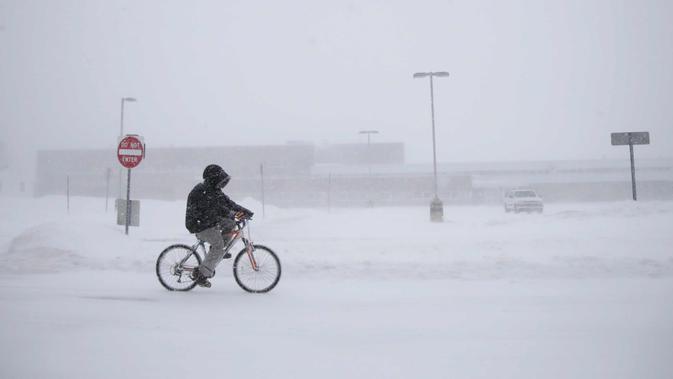 Justin Hartman mengendarai sepedanya saat badai musim dingin hebat di sepanjang New Bedford Road di Wall Township, NJ (4/1). Badai salju ini diperkirakan akan memecahkan rekor cuaca dingin yang pernah terjadi sebelumnya. (AP Photo / Julio Cortez)