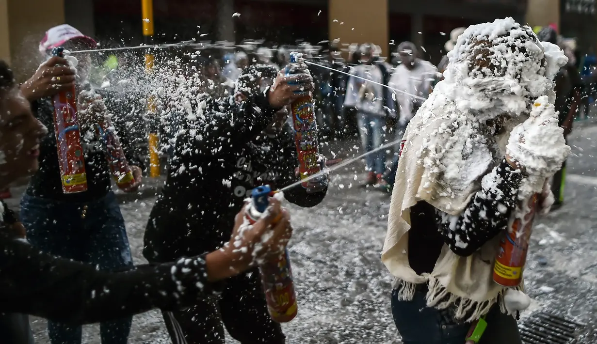 Sejumlah peserta Hari Hitam menyemprotkan busa kepada peserta lainnya di Pasto, Kolombia, (5/1). Lebih dari 10.000 peserta dari seniman, perajin, dan  wisatawan ambil bagian dalam karnaval Hari Hitam. (LUIS ROBAYO/AFP)