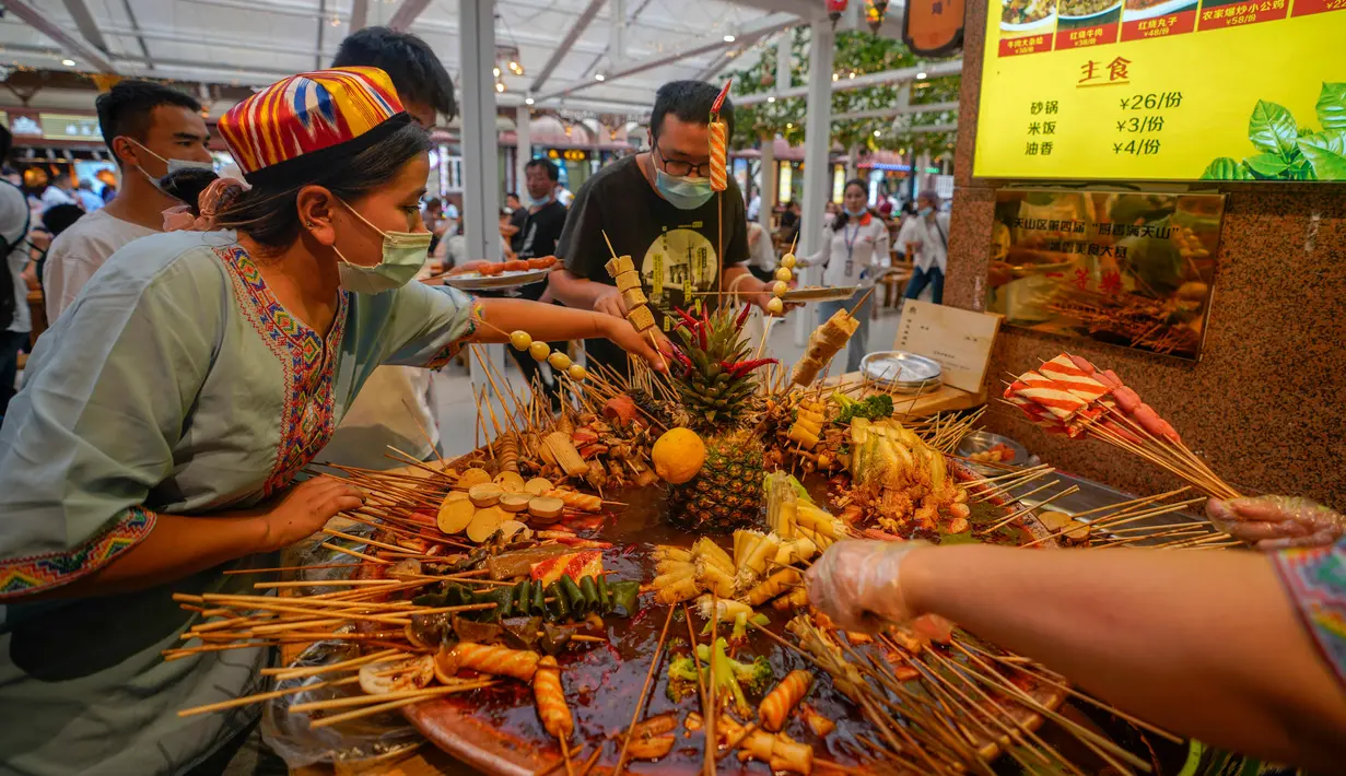 Para pengunjung memilih kudapan pedas di jalan camilan Grand Bazaar di Urumqi, ibu kota Daerah Otonom Uighur Xinjiang, China barat laut, pada 4 Juli 2020. (Xinhua/Zhao Ge)
