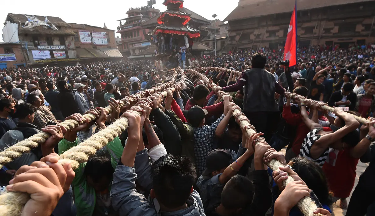 Umat Hindu Nepal menarik kereta kayu dewa Bhairava yang melewati kerumunan saat festival Bisket Jatra di Bhaktapur, Nepal (10/4). Festival ini diadakan untuk menandai Tahun Baru Nepal. (AFP Photo/Prakash Mathema)