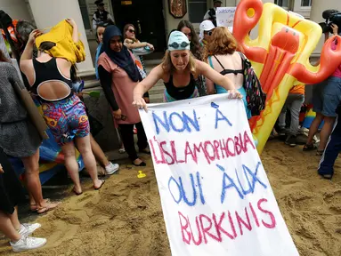 Sejumlah wanita mengadakan demonstrasi pesta pantai di luar kedutaan Prancis di London, Inggris, Kamis (25/8). Mereka memprotes larangan burkini (pakaian renang muslimah) yang diberlakukan di beberapa kota pesisir di Prancis. (REUTERS/Neil Hall)