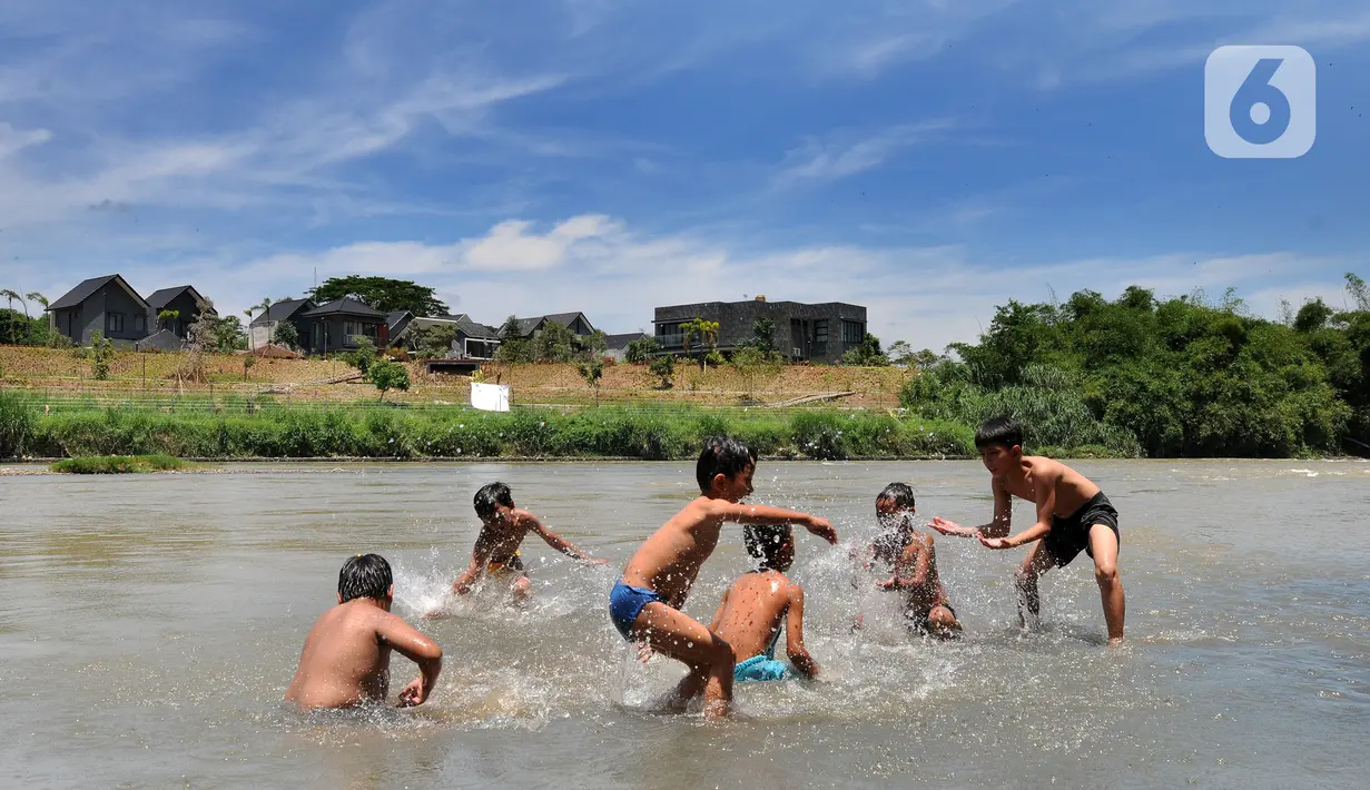 Anak-anak bermain pada aliran Sungai Cisadane di kawasan Keranggan, Setu, Tangerang Selatan, Banten, Minggu (20/3/2022). Cuaca panas terik dimanfaatkan mereka untuk berendam sambil bermain. (merdeka.com/Arie Basuki)