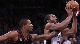 Pebasket Houston Rockets, Trevor Ariza, berusaha menghentikan pebasket San Antonio Spurs, Kawhi Leonard, pada laga semifinal wilayah barat NBA di AT&T Center, San Antonio, Rabu (3/5/2017). Spurs menang 121-96 atas Rockets. (AFP/Ronald Martinez)
