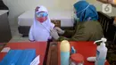 Petugas Puskesmas melakukan imunisasi campak kepada siswa kelas I saat pelaksanaan Bulan Imunisasi Anak Sekolah (BIAS) di SDN Serua 3, Ciputat, Tangsel, Selasa (1/9/2020). Kegiatan itu untuk memberikan kekebalan terhadap siswa dari penyakit campak, difteri dan tetanus. (merdeka.com/Dwi Narwoko)