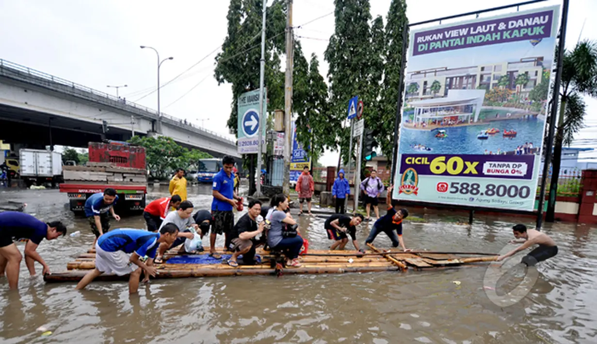 Tampak warga menyewakan perahu kayu kepada orang-orang yang ingin melintasi banjir, Jakarta, Senin (6/2/2015). Jasa gerobak Mematok harga Rp. 30 ribu untuk membawa motor sedangkan untuk per orang hanya Rp. 10 ribu. (Liputan6.com/Faizal Fanani)