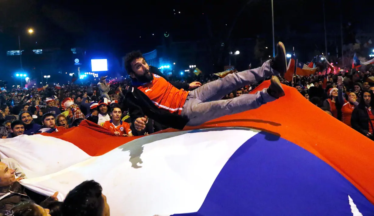 Sejumlah Suporter melemparkan suporter Chili di bendera nasional merayakan kemenangan Chili atas Argentina di final Copa Amerika 2015 di Santiago, (4/7/2015). Chili menang lewat adu penalti atas Argentina dengan skor 4-1. (REUTERS/Rodrigo Garrido)