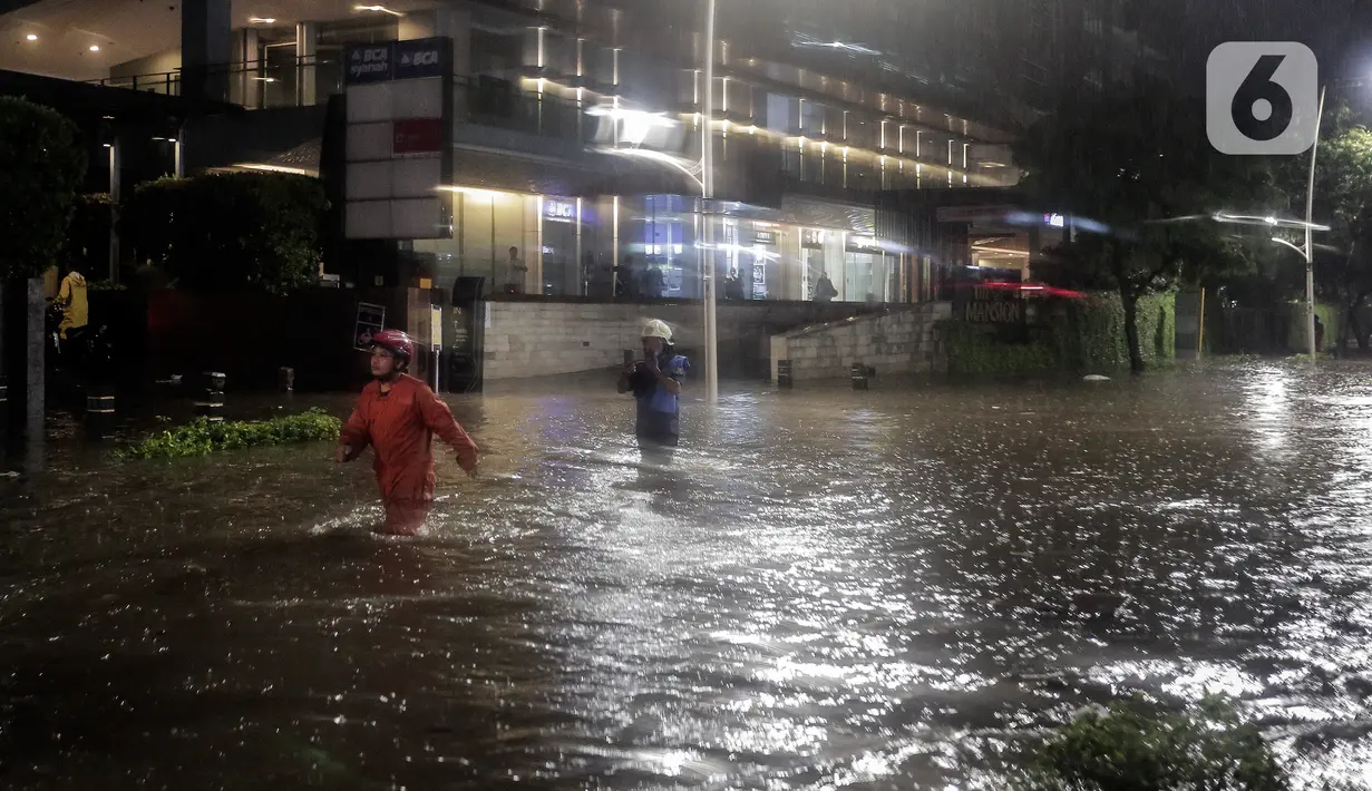 Warga melintasi banjir di Jalan Kemang Raya, Jakarta Selatan, Selasa (4/10/2022). Hujan yang mengguyur wilayah Ibu Kota Jakarta mengakibatkan banjir menggenangi kawasan Kemang, Jakarta. (Liputan6.com/Johan Tallo)
