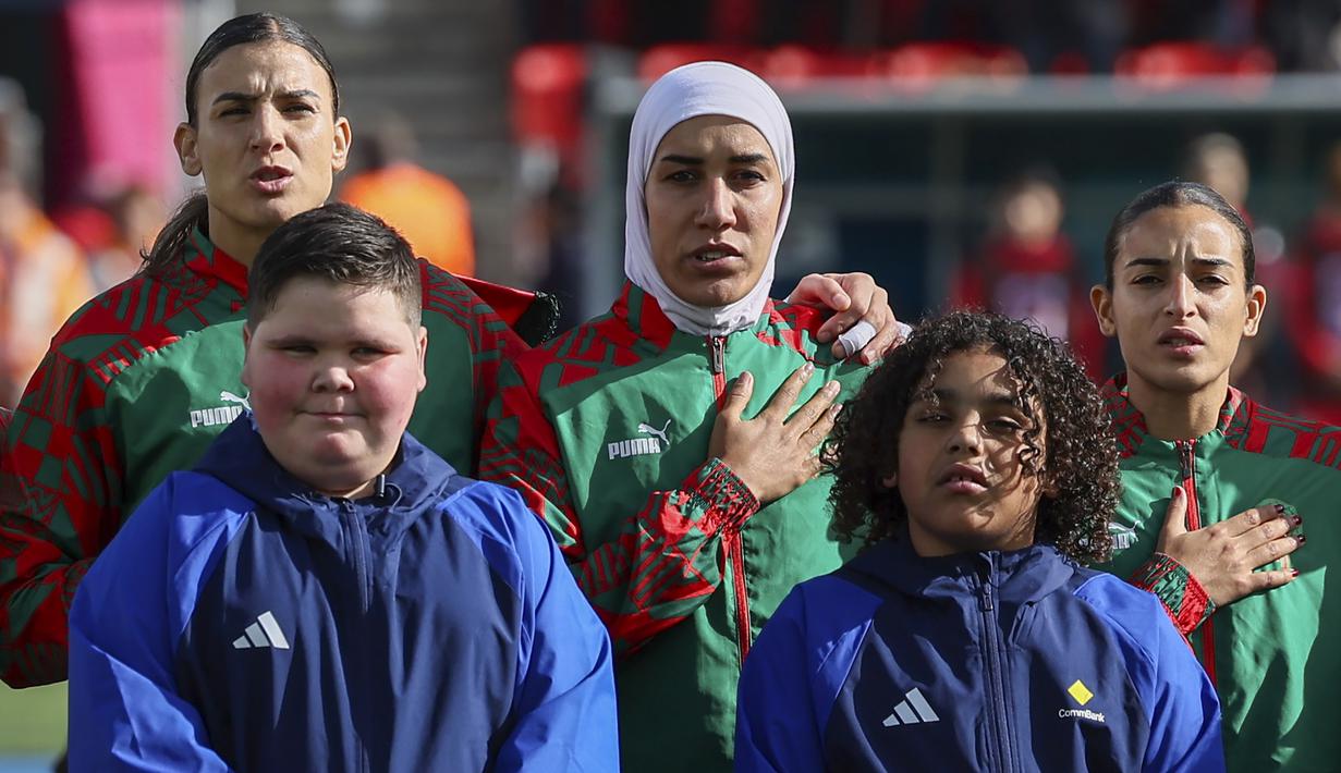 Pemain Timnas Sepak Bola Wanita Maroko, Nouhaila Benzina (tengah) bersama rekan setim berdiri menyanyikan lagu kenbangsaan Maroko sebelum dimulainya laga menghadapi Korea Selatan pada laga kedua Grup H Piala Dunia Wanita 2023 di Hindmarsh Stadium, Adelaide (30/7/2023). (AP Photo/James Elsby)