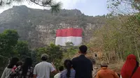 Bendera merah putih berukuran raksasa tampak berkibar dari atas tebing Mandala 125 Pabeasan, Bandung Barat, 17 Agustus 2024/Liputan6.com.