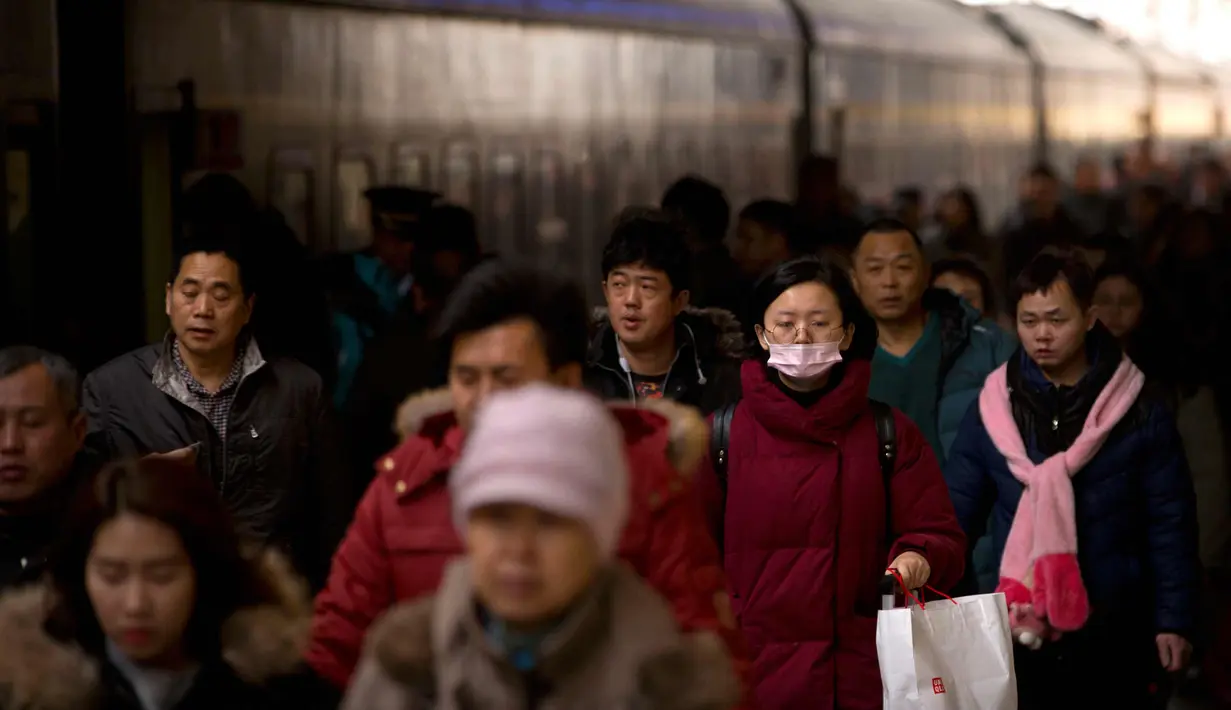Warga berjalan ke sebuah kereta di Stasiun Kereta Api Beijing, (9/2). Sambut perayaan Imlek 2018, Jutaan warga China mulai memenuhi stasiun, bandara dan jalan yang diperkirakan akan dimulai akhir pekan ini. (AP Photo / Mark Schiefelbein)