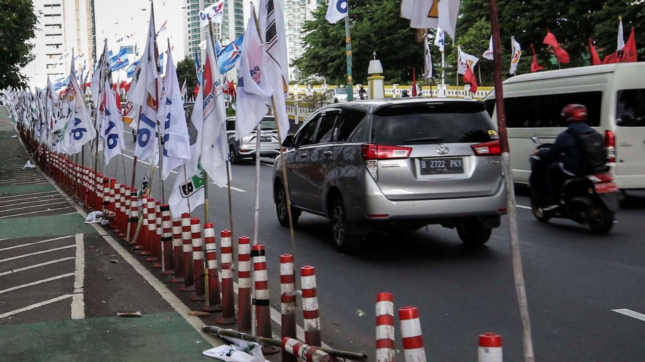 Ratusan alat peraga kampanye (APK) bendera partai politik terpasang di pembatas plastik jalur sepeda (stick cone) di kawasan Jalan Rasuna Said, Jakarta Selatan, Senin  (8/1/2024).