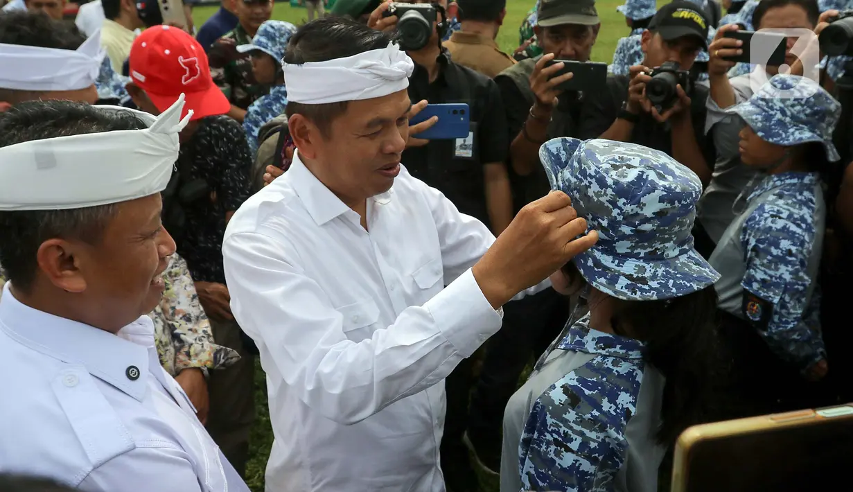 Gubernur Jawa Barat Dedi Mulyadi merapikan topi nan dikenakan salah satu siswa peserta program Pembinaan Karakter dan Bela Negara di lapangan Markas Divisi Infanteri 1 Kostrad, Cilodong, Kota Depok, Senin (9/6/2025). (detikai.com/Herman Zakharia)