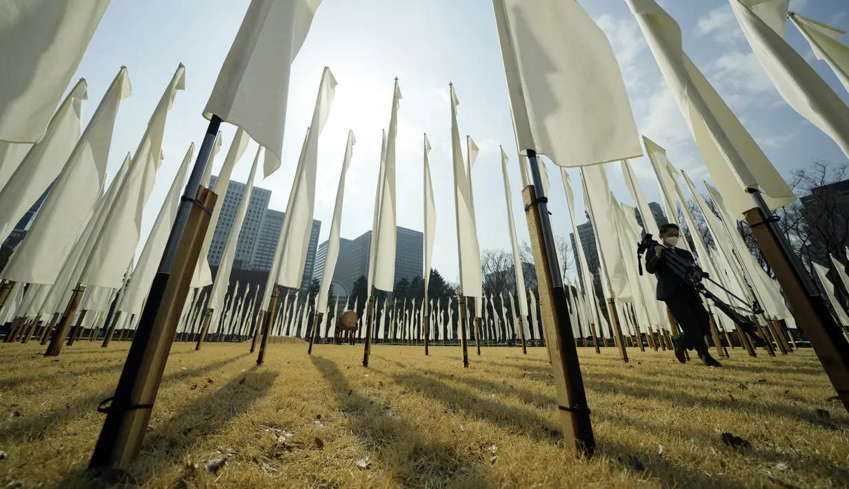 Seorang jurnalis berjalan melewati 311 bendera untuk berkabung bagi para korban gempa bumi dan tsunami 11 Maret 2011 dalam acara peringatan khusus di Tokyo, Jumat (11/3/2022). (AP Photo/Eugene Hoshiko)