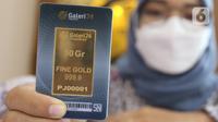Seorang petugas menunjukkan koleksi emas batangan di Galeri 24 Pegadaian, Jakarta, Jumat (25/3/2022). Harga emas yang dijual PT Aneka Tambang Tbk (ANTM) atau emas Antam kembali naik. Hari ini harga emas Antam naik Rp 6.000 menjadi Rp 1 juta per gram, pada 25 Maret 2022. (Liputan6.com/Angga Yuniar)