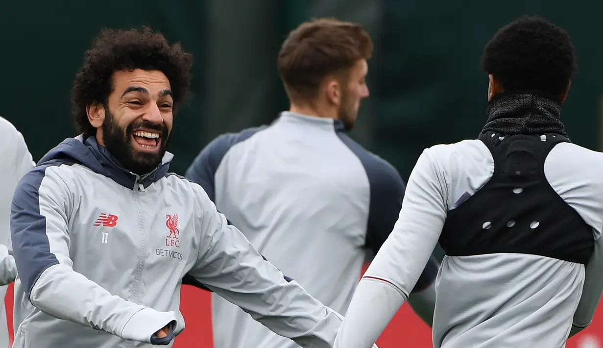 Gelandang Liverpool Mohamed Salah (kiri) bercanda dengan rekan setimnya saat sesi latihan jelang menghadapi Bayern Munchen dalam leg kedua babak 16 besar Liga Champions di Melwood, Liverpool, Inggris, Selasa (12/3). (Paul ELLIS/AFP)