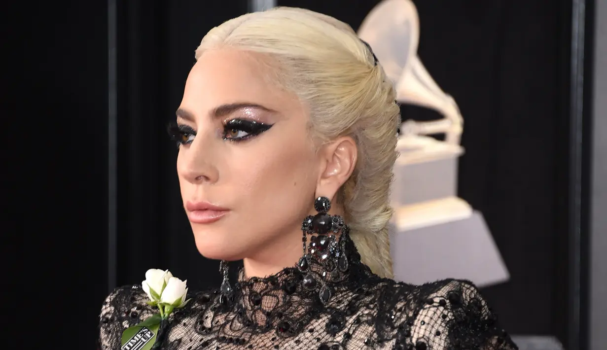Lady Gaga menyematkan mawar putih pada gaunnya ketika menghadiri karpet merah Grammy Awards 2018 di New York, Minggu (28/1). Bunga ini menjadi lambang dukungan melawan kesetaraan gender dan pelecehan seksual di industri musik (Evan Agostini/Invision/AP)