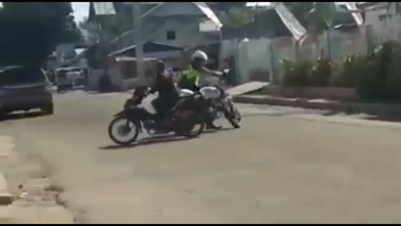 pengendara sepeda motor diberhentikan polisi yang sedabng berpatroli karena melanggar peraturan.