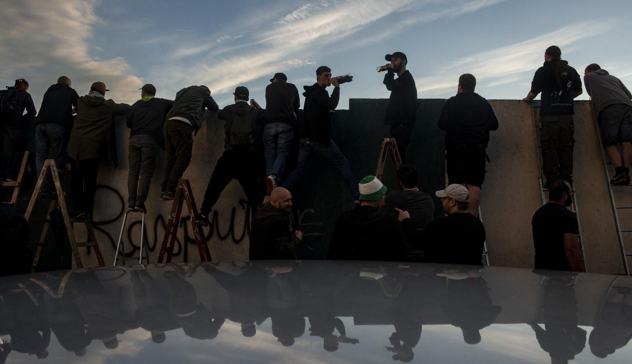 Suporter Bohemians 1905 menyaksikan pertandingan melawan Sparta Praha pada laga Liga Fortuna di Praha, Rep. Ceko (6/6/2020). Laga tertutup karena pembatasan virus corona tersebut membuat fans menonton dari balik tembok. (AFP/Michal Cizek)