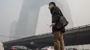 Warga mengenakan masker saat kabut asap menyelimuti Beijing, China, Senin (30/11). Pemerintah setempat mengumumkan keadaan siaga dan menyarankan warga Beijing untuk berada dalam rumah karena kandungan polusi udara yang berbahaya. (AFP PHOTO/ FRED DUFOUR)