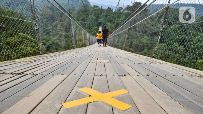 Tanda jaga jarak terpasang di lantai Jembatan Gantung Situ Gunung, Sukabumi, Jawa Barat, Minggu (20/9/2020). Dari rata-rata 2.500 pengunjung tiap harinya kini hanya di bawah 1.000 pelancong per hari akibat merebaknya pandemi Covid-19 serta adanya penerapan PSBB. (merdeka.com/Iqbal S. Nugroho)