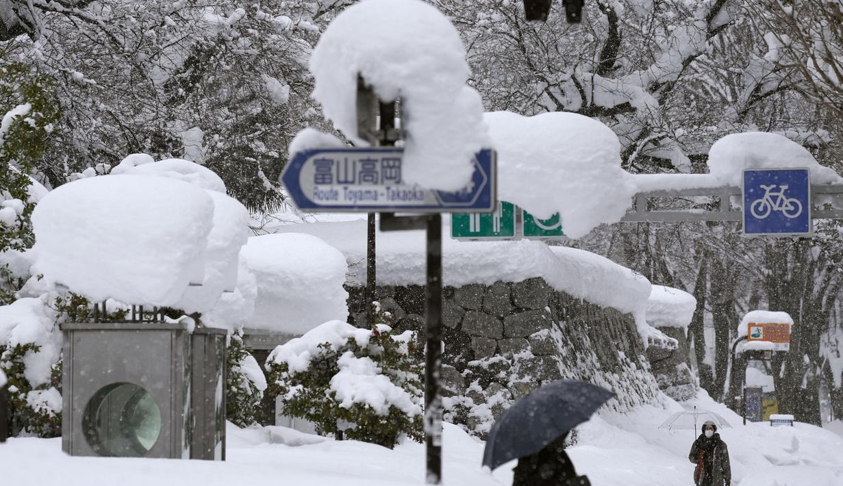 Orang-orang berjalan di atas salju yang menumpuk di kota Toyama, di pesisir Laut Jepang, Senin (11/1/2021). Sedikitnya delapan orang tewas dan sekitar 240 lainnya luka-luka saat badai musim dingin yang kuat melanda daerah pesisir di sepanjang Laut Jepang. (Kyodo News via AP)