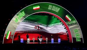 Asisten pengundian, Tom Brady, Asisten pengundian, Shaquille O’Neal, Konduktor Samantha Johnson, Legenda FIFA, Rio Ferdinand, Asisten pengundian, Aaron Judge, dan Asisten pengundian, Wayne Gretzky berdiri di atas panggung saat Iran ditampilkan di layar selama Pengundian Resmi Piala Dunia 2026 di John F. Kennedy Center for the Performing Arts pada 5 Desember 2025 di Washington, DC. (Kevin Dietsch/Getty Images via AFP)