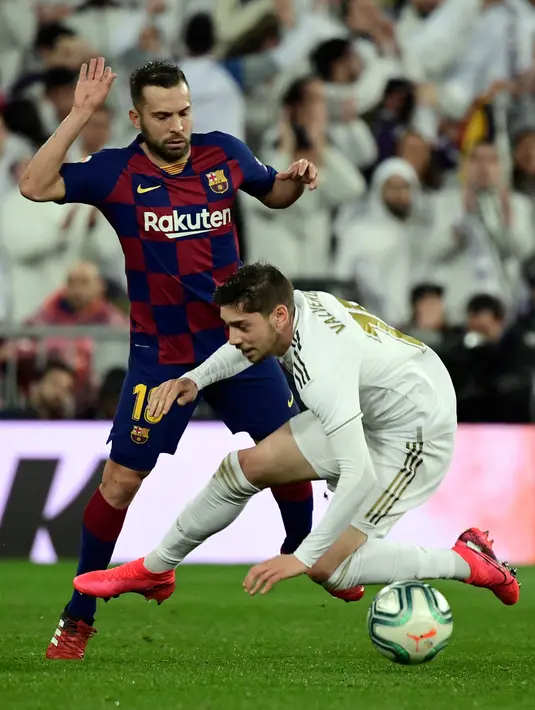 Bek Barcelona, Jordi Alba (kiri) berebut bola dengan gelandang Real Madrid, Federico Valverde pada lanjutan pertandingan La Liga di Santiago Bernabeu, Minggu (2/3/2020).  Real Madrid membungkam Barcelona 2-0 dan merebut puncak klasemen dari Barcelona. (JAVIER SORIANO/AFP)