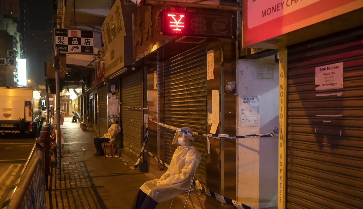 Petugas kesehatan mengenakan APD berjaga di area tertutup di distrik Jordan, di Hong Kong, Minggu (24/1/2021). Kawasan tersebut telah mengkonfirmasi 162 kasus COVID-19 yang dikonfirmasi bulan ini. (AP Photo/ Kin Cheung)