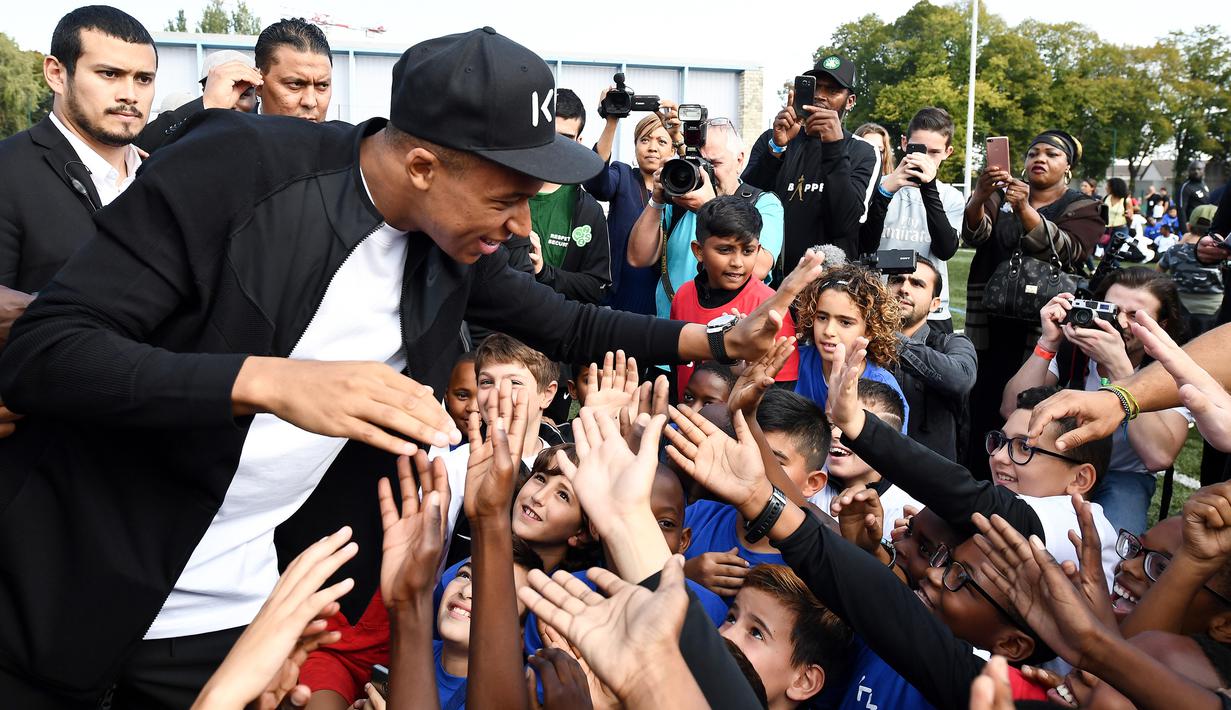 Bintang Prancis, Kylian Mbappe, menyapa anak-anak saat mengunjungi markas AS Bondy di Paris, Rabu (17/10). Kunjungan ke klub pertamanya ini dilakukan setelah dirinya meraih gelar Piala Dunia 2018. (AFP/Franck Fife)