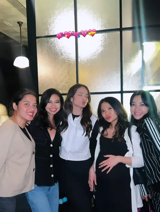 Ia mengenakan fitted dress hitam panjang dengan vest berkantung dan boots putih [@enzystoria]