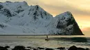 Peselancar menikmati gelombang ombak saat berselancar di pantai bersalju Flackstad di Kepulauan Lofoten, Lingkar Arktik, pada 12 Maret 2016. Suhu laut mencapai 5 derajat celcius dan suhu udara hingga 0 derajat celcius. (AFP/Olivier Morin)