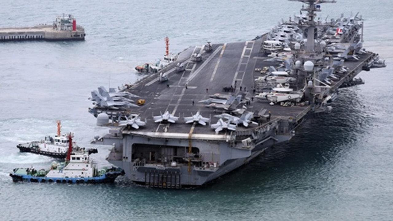 Kapal induk USS Carl Vinson dikawal ke pelabuhan angkatan laut di Busan, Korea Selatan, Minggu (2/3/2025).