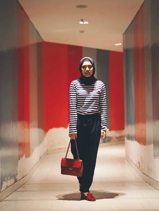 Seperti yang dilakukannya ini, Herfiza memakai celana hitam yang dipadukan dengan kaus bermotif garis-garis. Penampilannya terlihat cerah lantaran ia memadukannya dengan tas berwarna merah yang senada dengan sepatunya. (Instagram/herfiza)