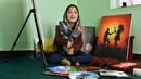 Seniman Robaba Mohammadi duduk di sebelah lukisannya selama wawancara dengan AFP mulut di studionya di Kabul pada 5 Desember 2019. Melalui lukisan, seniman asal Afghanistan ini mengekspresikan bahwa wanita dan disabilitas bukan lagi hal yang bisa dipandang sebelah mata. (NOORULLAH SHIRZADA/AFP)