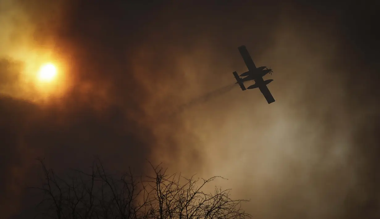 Sebuah pesawat menjatuhkan air saat terjadi kebakaran di Cordoba, Argentina, Senin (12/10/2020). Kebakaran hutan telah menghancurkan ribuan hektare di Provinsi Cordoba tahun ini, di tengah kekeringan dan suhu tinggi. (AP Photo/Nicolas Aguilera)