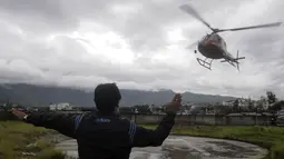 Petugas mengarahkan helikopter yang membawa korban tewas setibanya di sebuah rumah sakit di Ibu Kota Nepal, Kathmandu, Senin (8/8). Tujuh orang, termasuk bayi dan pilot tewas akibat jatuhnya Helikopter Fishtail Air. (AFP PHOTO/BIKASH Karki)