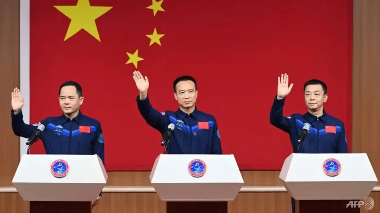 Astronot China Fei Junlong (tengah), Deng Qingming (kanan) dan Zhang Lu (kiri), awak misi penerbangan luar angkasa Shenzhou-15, melambai pada konferensi pers sebelum peluncuran. (Foto: CNS/AFP)