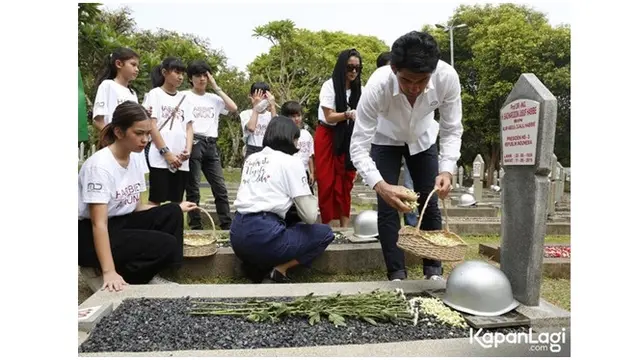 Reza Rahardian tampak menaburkan bunga di makam Habibie dan Ainun.