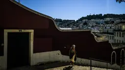 Seorang wanita berjalan melewati Escadinhas do Duque di Lisbon (14/7/2021). Hampir setengah dari populasi Portugal diberlakukan jam malam lagi awal bulan ini. (AFP/Patricia De Melo Moreira)